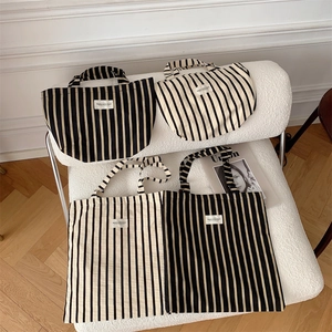 Detailed view of striped canvas tote bags in different sizes on a textured white sofa