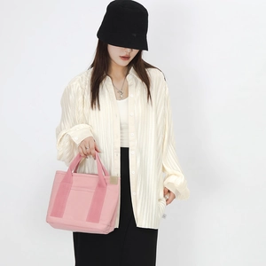 Lifestyle shot of a pink canvas tote bag styled with a pleated shirt and a long black skirt