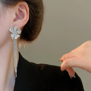 Macro detail of long silver flower tassel earrings with white pearls and snake chains