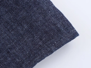 Détail du tissu denim bleu foncé montrant la texture sergée et la double couture