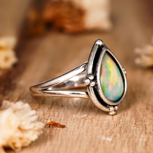 Vue macro latérale d'une bague vintage en argent avec opale en forme de poire sur bois