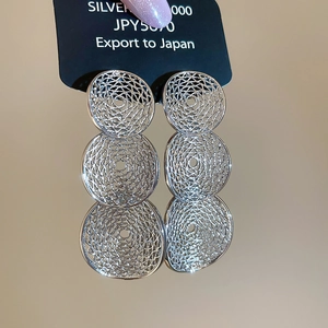 Detail of silver triple-layered hollow circular drop earrings with textured woven pattern