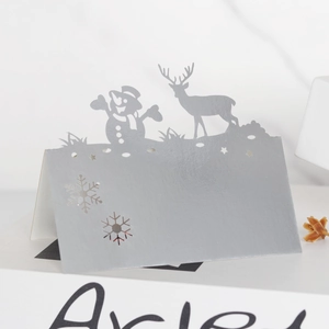Detail of silver laser-cut Christmas table cards with snowman and reindeer patterns