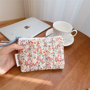Detailed texture of floral quilted cotton pouch with blue hand strap and small zip
