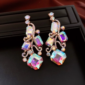 Close-up of golden drop earrings with square iridescent crystals and rhinestones