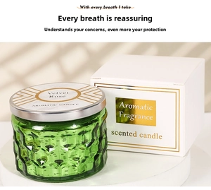 Detailed view of an embossed green glass candle jar with a silver lid and velvet rose scent