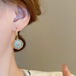 Detailed close-up of retro floral enamel earrings with zircon on woman's ear