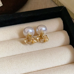 Detailed macro view of pearl stud earrings with golden wavy petals and zircon accents