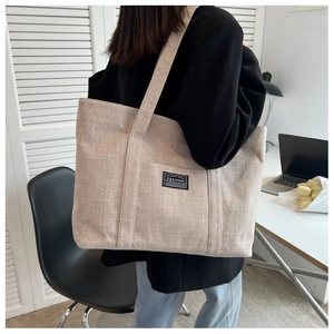 Macro detail of beige canvas tote bag with black fashion label on side pocket