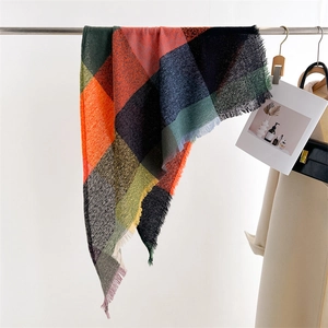 Detail of multi-color plaid scarf with soft fringe trim on a metal hanger