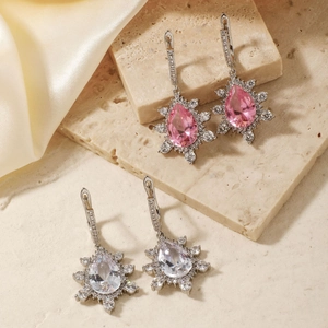 Macro shot of snowflake water drop earrings with pink and clear crystals on silk
