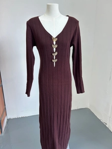 Détail du col en V sur robe en maille rouge foncé avec boucles dorées en demi-lune