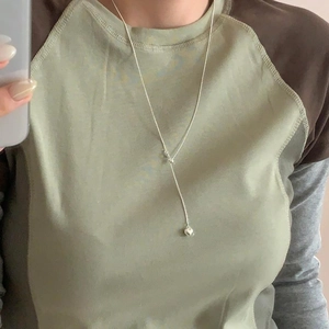 Detail view of a minimalist silver heart pendant necklace worn on a model's neck