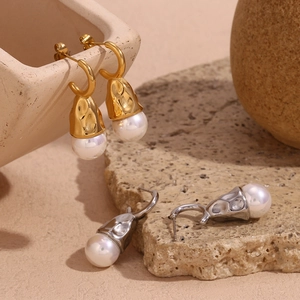 Close-up of hammered gold and silver teardrop earrings with elegant pearl pendants