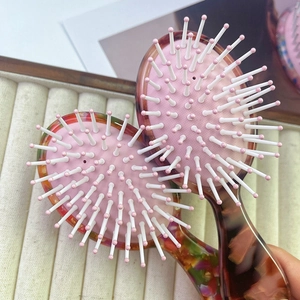 Close-up of portable acetate hairbrushes with colorful handles and soft pink air cushions