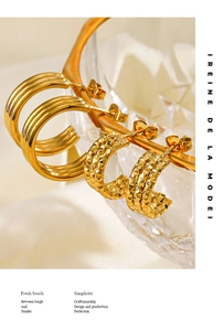 Detail of gold C-shaped earrings with smooth and hammered textures on glass edge