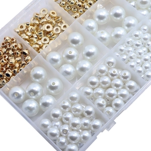 Top view of jewelry making kit with white faux pearls and gold spacers in organizer box