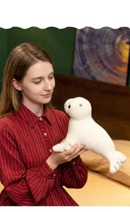 Détail d'un phoque en peluche blanche tenu dans un environnement intérieur chaleureux