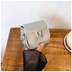 Close-up of a silver mini flap bag with metallic chain and 3D butterfly buckle