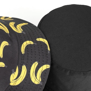 Detail of yellow banana prints on a black reversible bucket hat with fine stitching