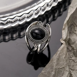 Detailed view of a vintage oval black stone ring with intricate braided silver texture