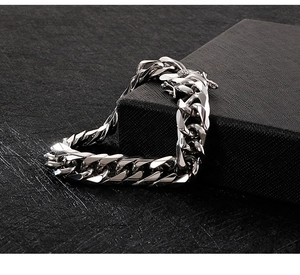 Macro detail of silver stainless steel Cuban link chain over black textured box