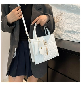 White quilted handbag with gold hardware and mini purse charm shown on model