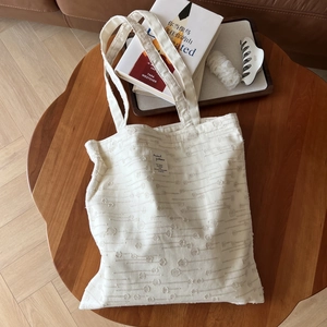 Detailed view of white cotton linen tote bag with textured dots on a dark wooden table