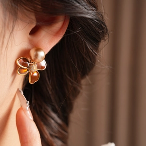 Gros plan sur des boucles d'oreilles fleur dorée avec pétales ambre et perle