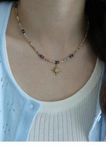 Close-up of star pendant necklace with crystal beads on a model wearing blue knitwear