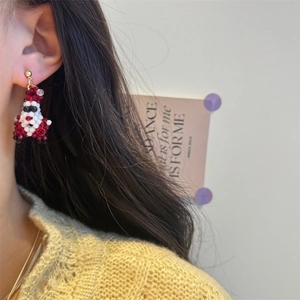 Close-up of handmade beaded Santa Claus earring worn by a model for holiday style