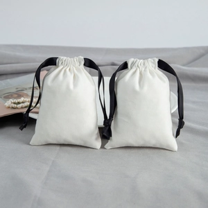 Detail of two white cotton drawstring gift bags with black satin ribbons and pearls