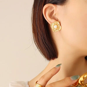French style gold flower stud earrings with pearl center on model's ear lobe