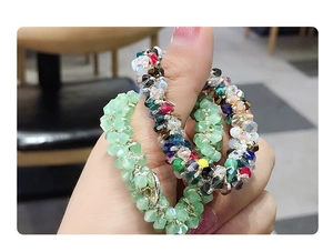 Gros plan de chouchous élastiques en perles de cristal vert clair et multicolores au poignet