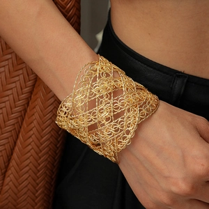 Close-up of golden hollow woven mesh cuff bracelet worn on wrist with intricate texture