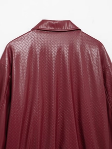 Detailed view of burgundy woven faux leather texture on a retro bomber jacket