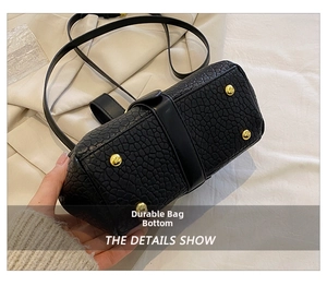 Detail of black textured leather handbag bottom with four protective gold metal feet