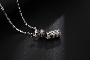 Dettaglio macro del ciondolo a croce in acciaio inox argento con chiusura magnetica