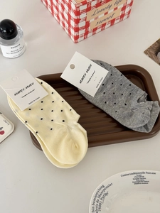 Gros plan de chaussettes en coton à pois beige et gris sur un plateau décoratif