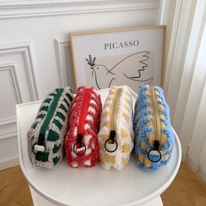 Flat lay of four checkered waffle plush stationery bags with zipper pulls on a round table