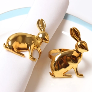 Golden rabbit napkin rings set on white cloth and ceramic plate for Thanksgiving table