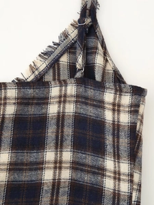 Detail of plaid dress showing adjustable straps and frayed fringe neckline texture