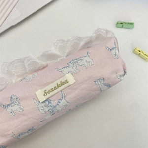 Close-up of pink fabric pencil case with lace trim and blue cat prints and woven label