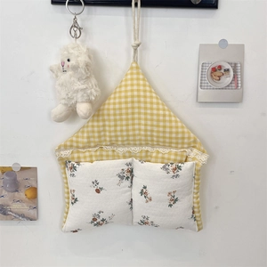 Detail of house-shaped wall storage bag in yellow plaid with floral lace pockets