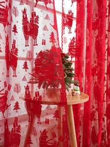 Close-up of red lace Christmas curtain featuring Santa, tree patterns and Happy Holidays text