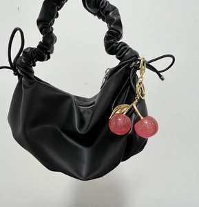 Detail of pink glitter cherry charm with gold leaves on a black ruched cloud bag