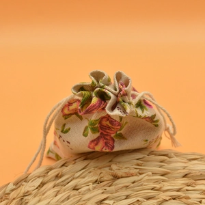 Detail of floral printed linen drawstring pouch for jewelry storage on a woven mat