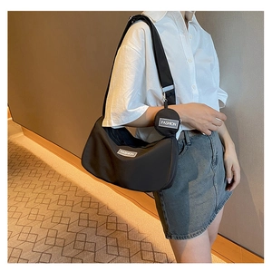 Detail of black nylon crossbody bag with wide shoulder strap and round coin purse charm