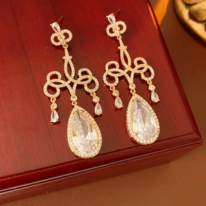 Gros plan sur des boucles d'oreilles dorées avec nœud élégant et zircon en goutte