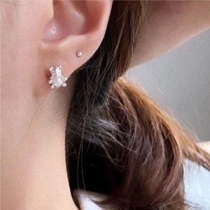 Detail of silver bear earring with pearl accent and minimalist ball stud on ear